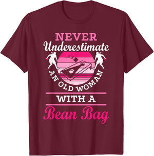 Never Underestimate An Old Woman With A Bean Bag Cornhole T-Shirt - T-Shirt | Maroon